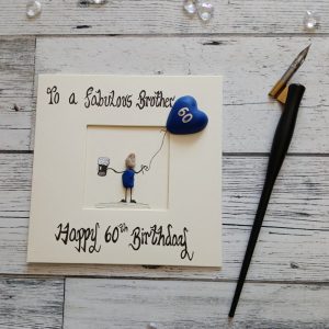 Luxury pebble art card 60th card for a brother, handwritten using black ink, To a fabulous Brother Happy 60th birthday, male pebble figure holding a beer and a blue heart balloon. Created on cream card.