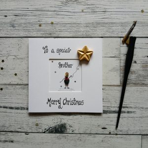 Handmade pebble art card Christmas card for Brother, handwritten using black ink, To a special Brother, Merry Christmas. Male pebble figure holding a star shaped balloon. Created on white card.