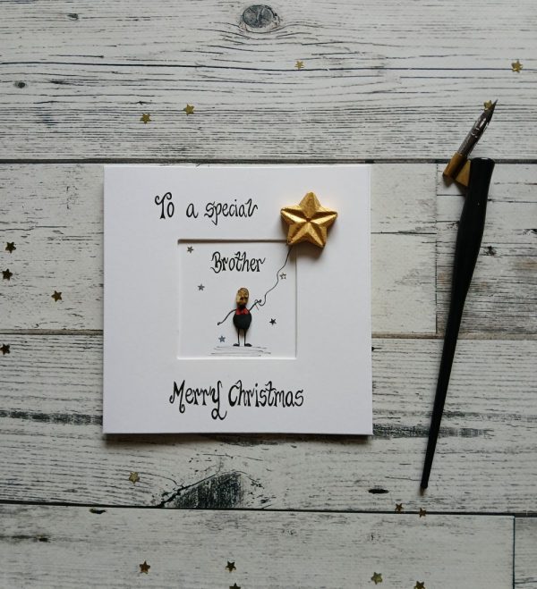 Handmade pebble art card Christmas card for Brother, handwritten using black ink, To a special Brother, Merry Christmas. Male pebble figure holding a star shaped balloon. Created on white card.