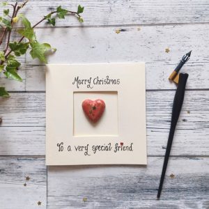 Handmade Christmas card for special friend, handwritten using black ink, Merry Christmas, To a very special friend. Placed in the centre of the card red heart shaped pebble. Created on cream card.