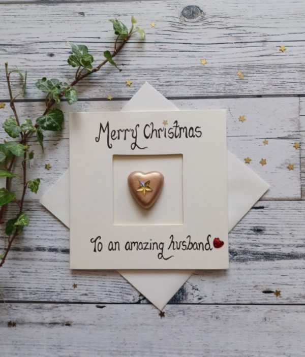 Handmade Christmas card for Husband, handwritten using black ink, Merry Christmas, To an amazing Husband. Placed in the centre of the card gold heart shaped pebble. Created on cream card.