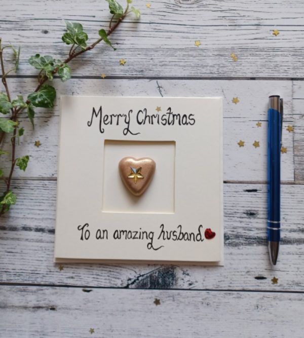 Handmade Christmas card for Husband, handwritten using black ink, Merry Christmas, To an amazing Husband. Placed in the centre of the card gold heart shaped pebble. Created on cream card.